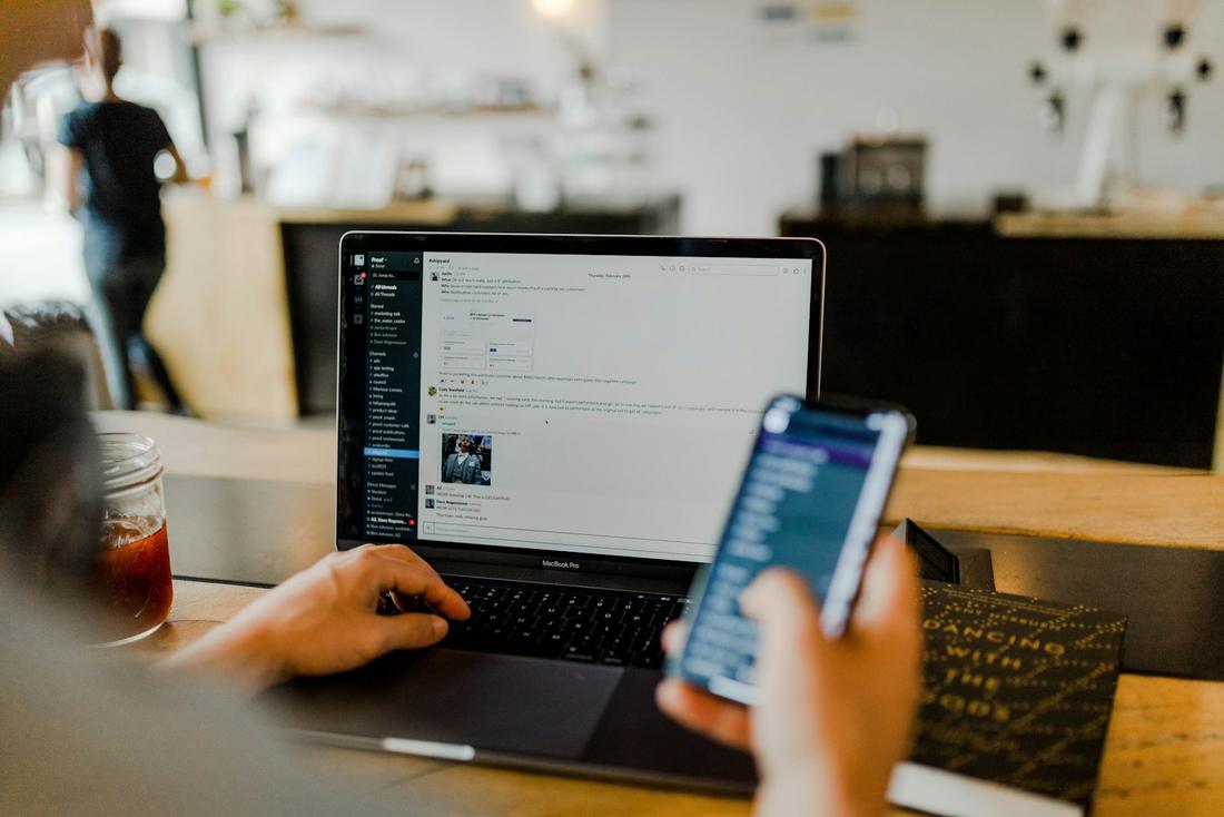 Customer browsing on a phone and laptop in a café